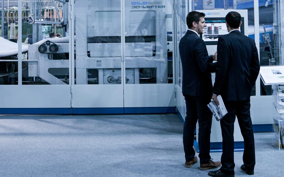 Two professionals discussing industrial machinery at a manufacturing trade show booth